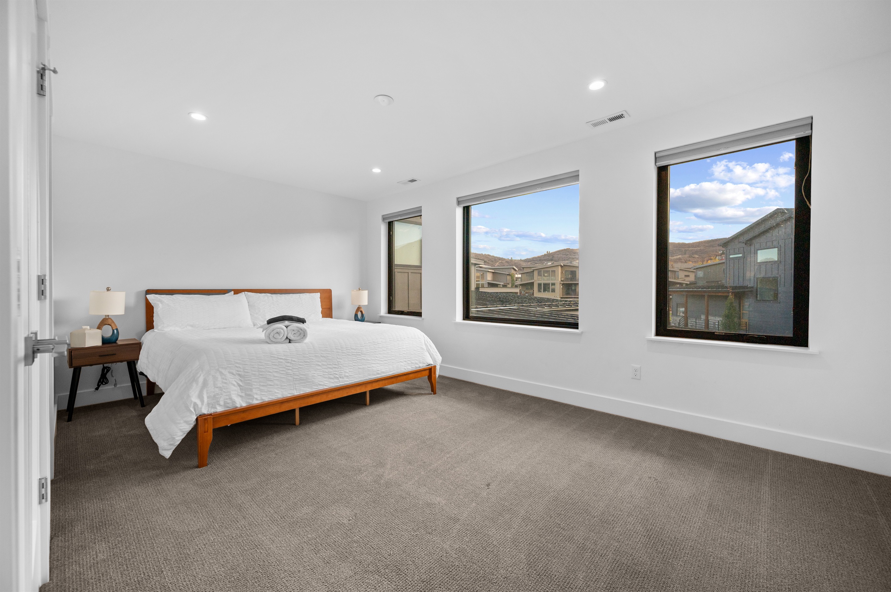 Bright upstairs bedroom with king bed and large windows offering natural light and mountain views