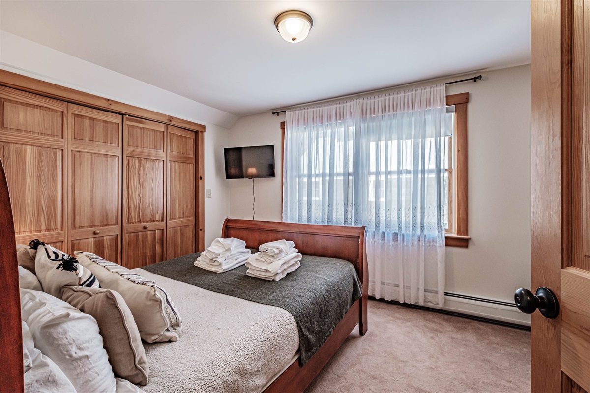 Second-floor queen bedroom with a comfortable queen bed, cozy crib, and convenient workspace.