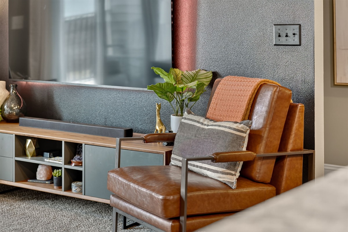 Modern media console and leather chair with décor accents. Custom touches transform this space into a chic condo-inspired retreat.
