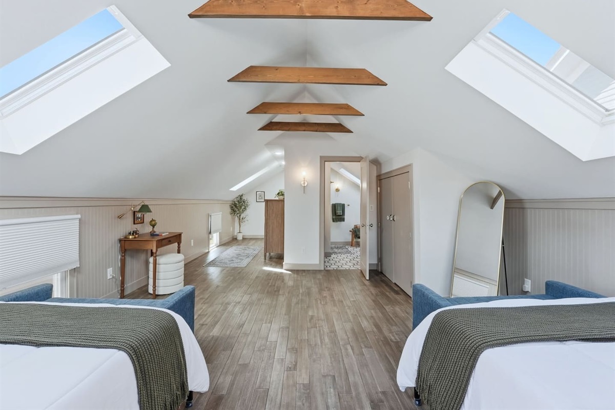 Wide-angle view highlighting the open layout, modern décor, and easy access to the bathroom from this large upstairs bedroom.