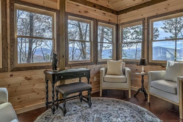 Sunlit sitting room with panoramic windows and mountain views - an ideal spot to read, relax, or work remotely.