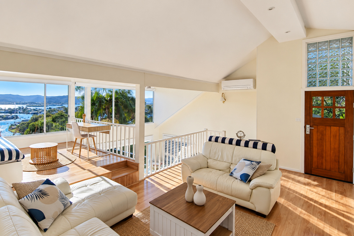 Bright, spacious living area with comfortable seating, a cosy window daybed and sweeping water and mountain views.