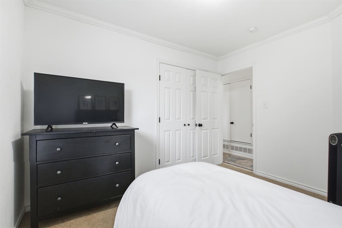 Bedroom with single bed, fresh linens, Smart TV, and room darkening shades for comfortable rest.