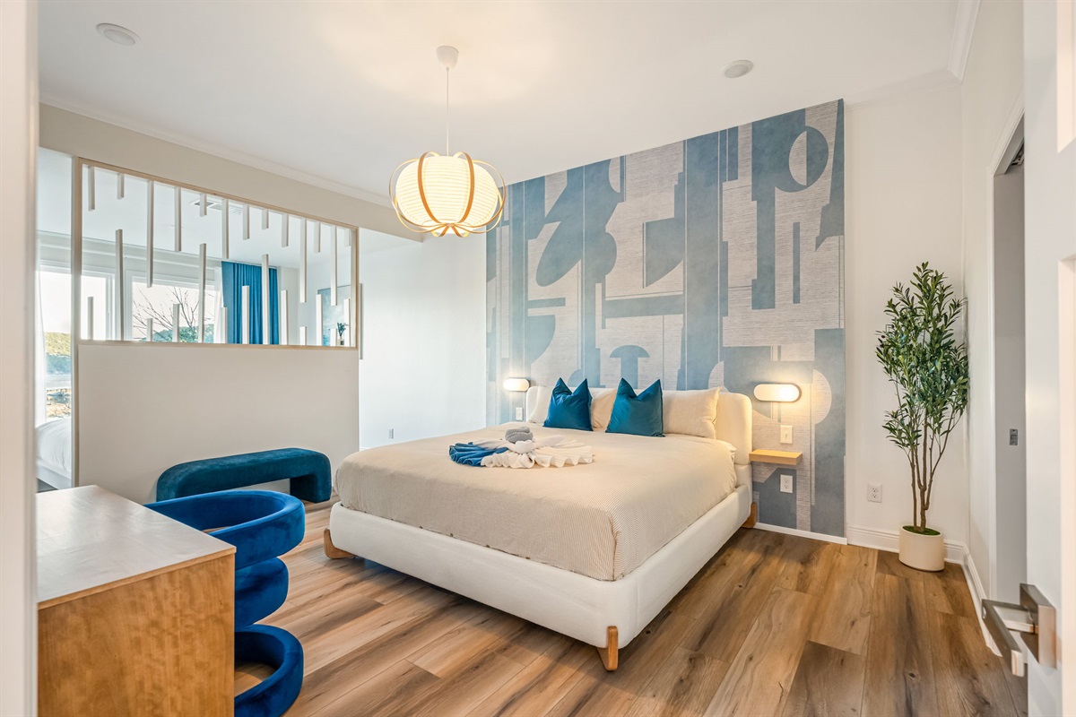 Spacious primary bedroom with plush king bed, stylish accent wall, and bright natural light.
