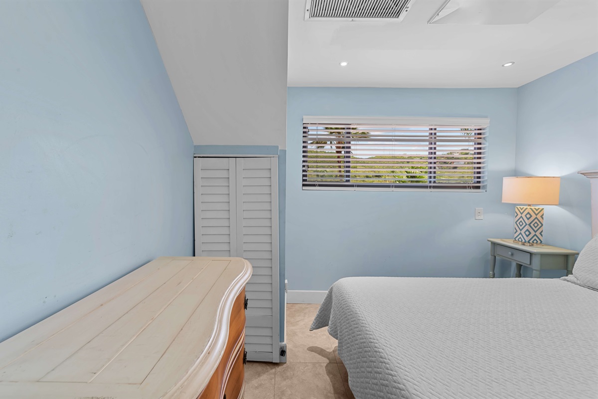 The guest bedroom has a queen bed and is across from the primary bedroom