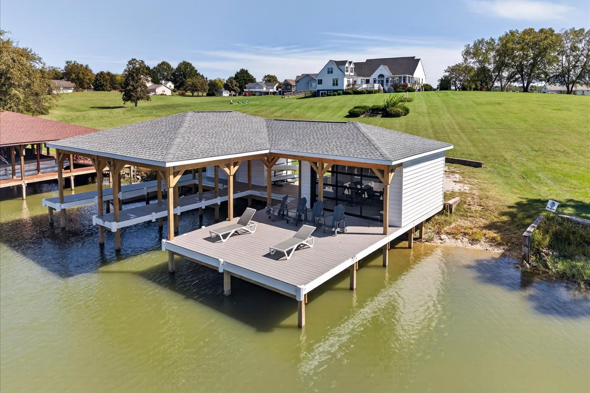 Waterside view of the boathouse with covered slips and shoreline lounging area.