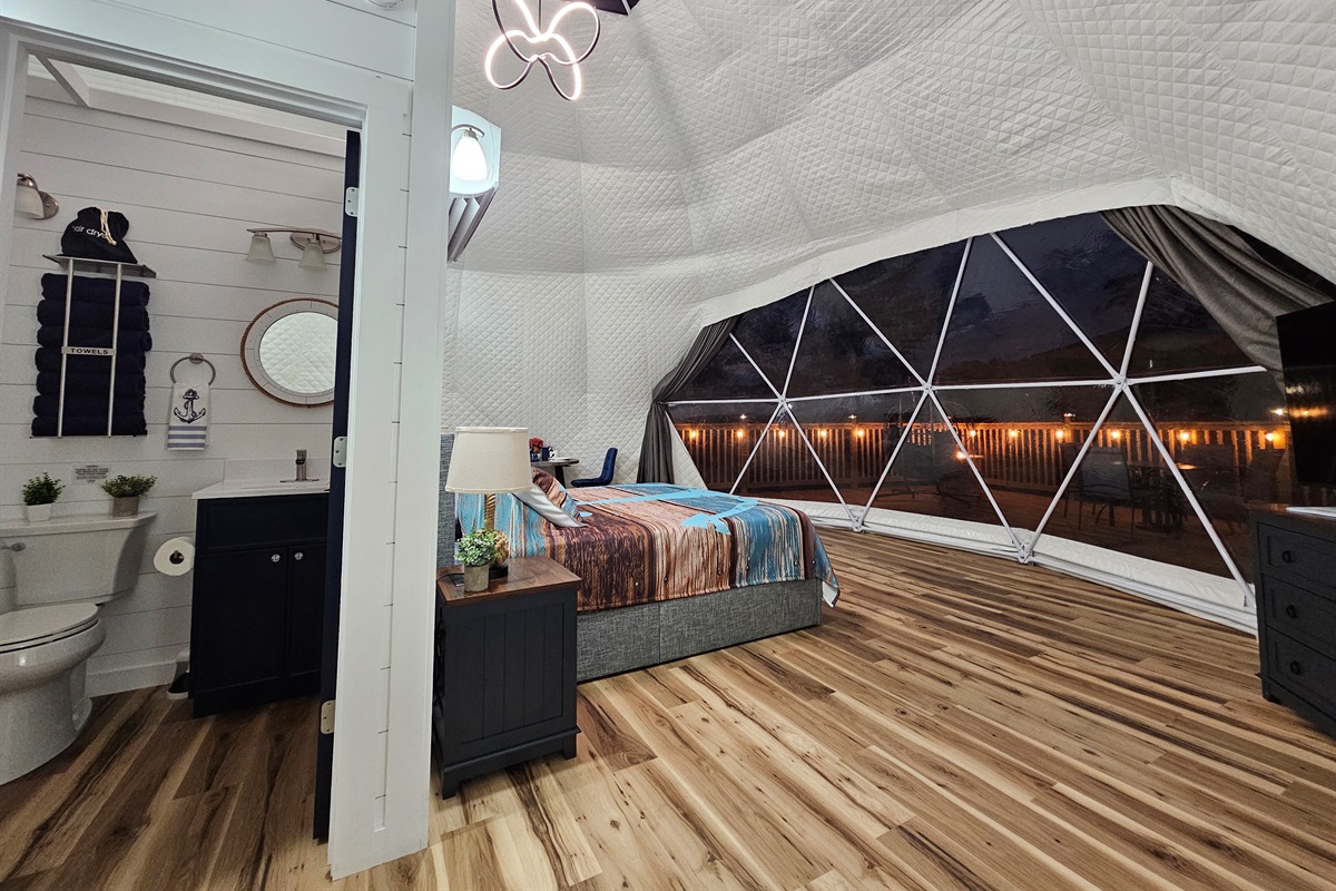 Cozy open-concept layout with private bathroom and stunning nighttime dome views overlooking the lights of the deck
