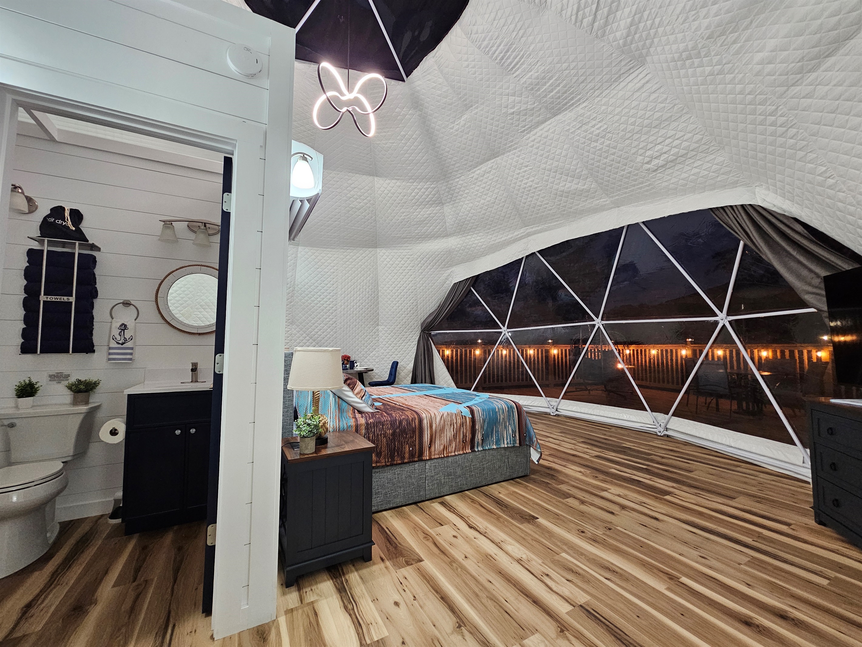 Cozy open-concept layout with private bathroom and stunning nighttime dome views overlooking the lights of the deck