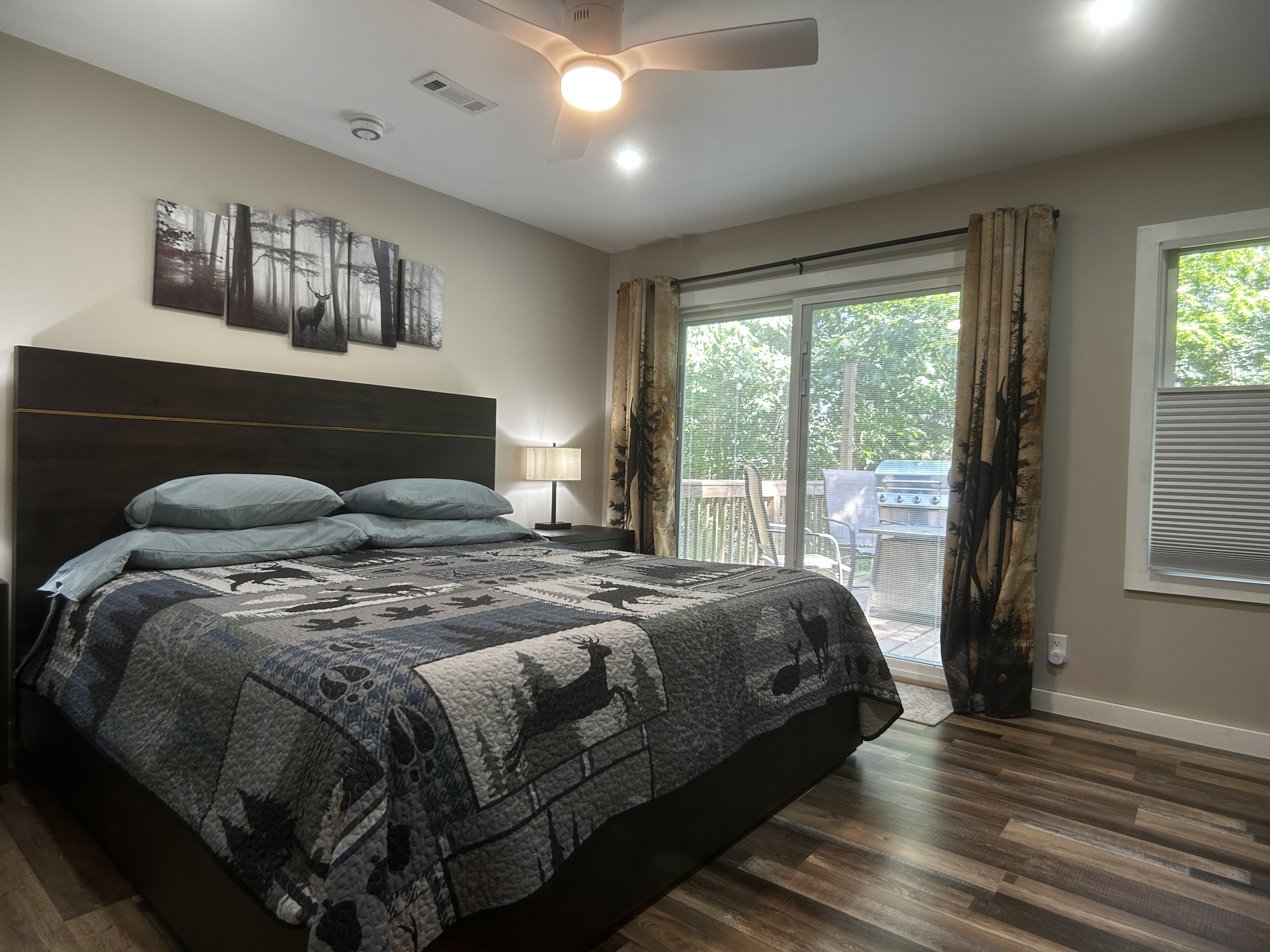 The king size bed has cotton sheets with high thread count. The room has dimmable lights, room darkening curtains and ceiling fan. Storage spaces include open shelving, dresser, side tables and closet space. Patio door leads to private deck with hot tub.