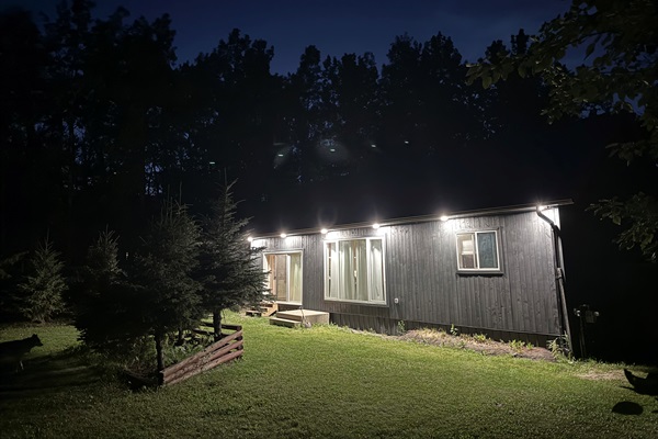 Side view of the cabin at night surrounded by forest