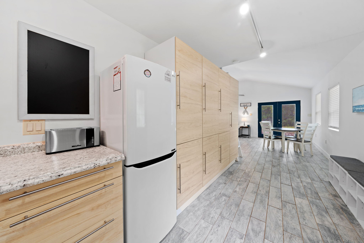 Open layout with a fridge and plenty of cabinet space connecting the kitchen, dining, and living spaces