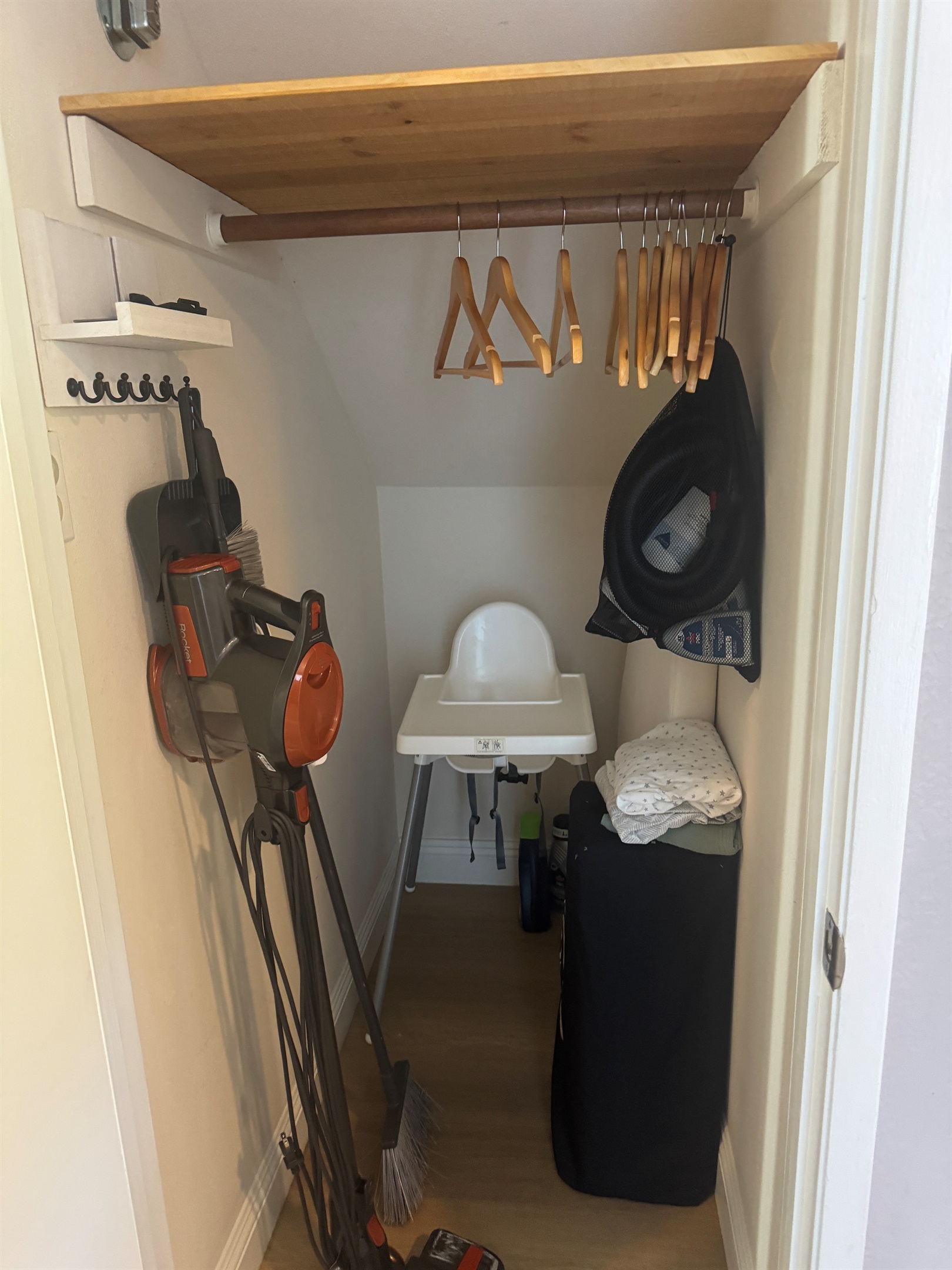 Baby supplies including pack n play (with sheets) and high chair in coat closet.