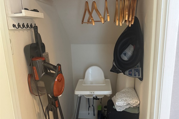 Baby supplies including pack n play (with sheets) and high chair in coat closet.