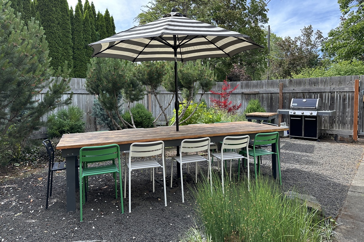 Outdoor dining table for 12 in fenced back yard, with Weber propane BBQ.