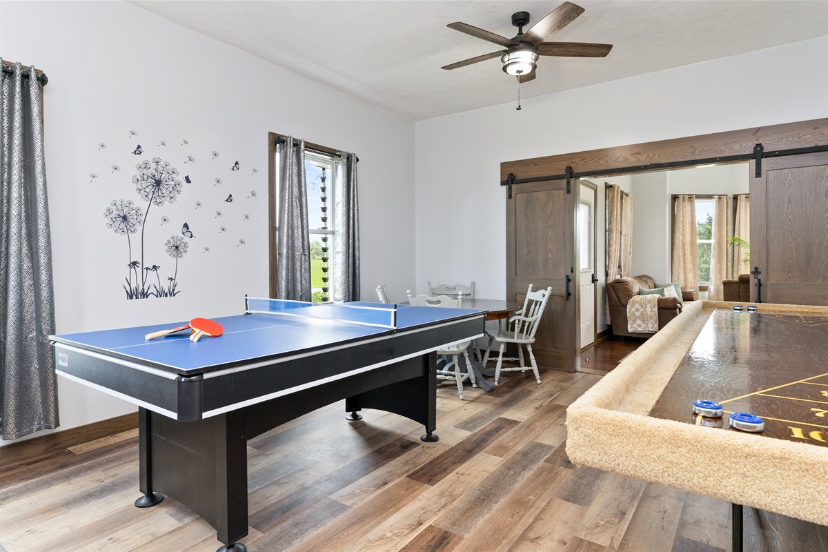 Entertainment-ready game room featuring a combination ping pong/pool table, shuffleboard, and air hockey with several board games and Cornhole for outside..... endless fun!
