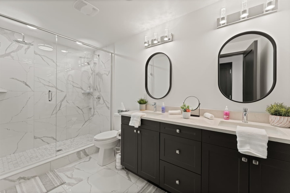 Large mirrors and black accents highlight contemporary luxury in the 3rd floor master ensuite bath.