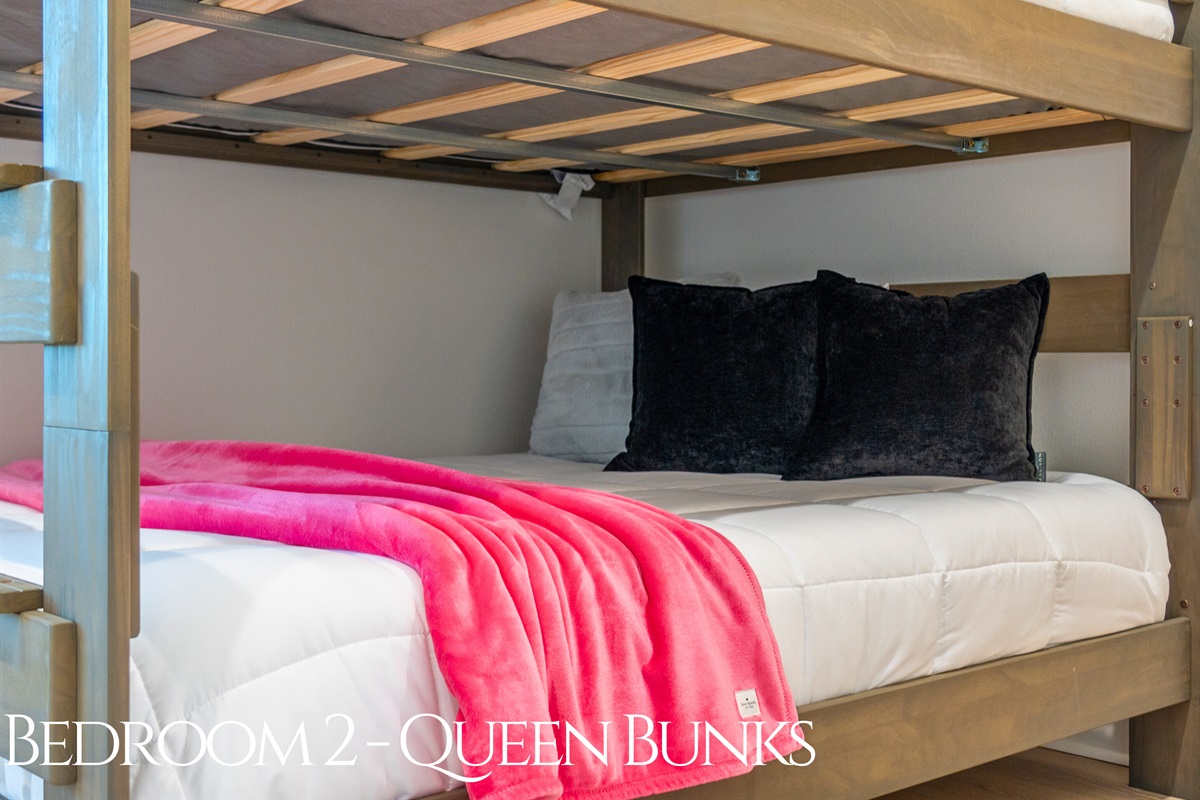 This playful bunk room features queen-over-queen beds, soft pops of color, and natural light, making it a cozy and functional retreat.