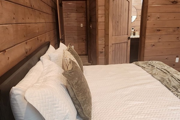 Queen bedroom with accent wall, reading lamps, and ensuite access.