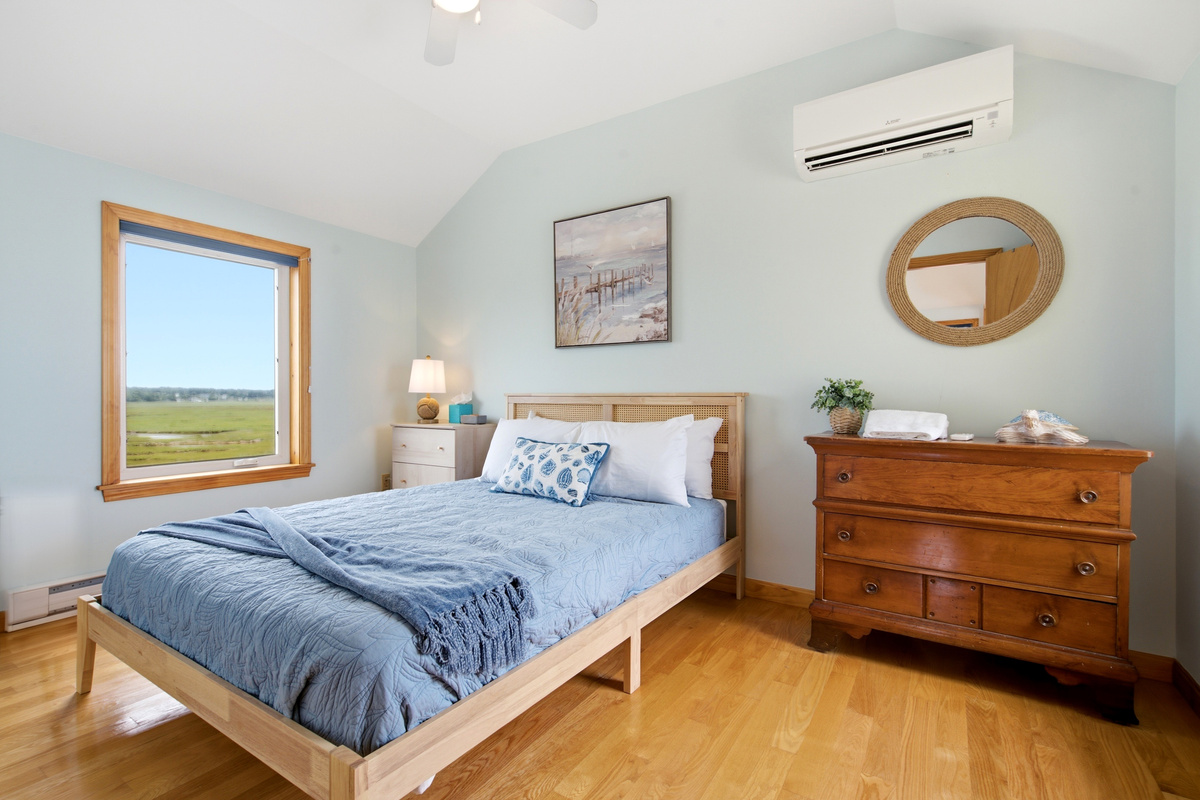 Peaceful bedroom with a queen bed, vaulted ceilings, and calming coastal décor.
