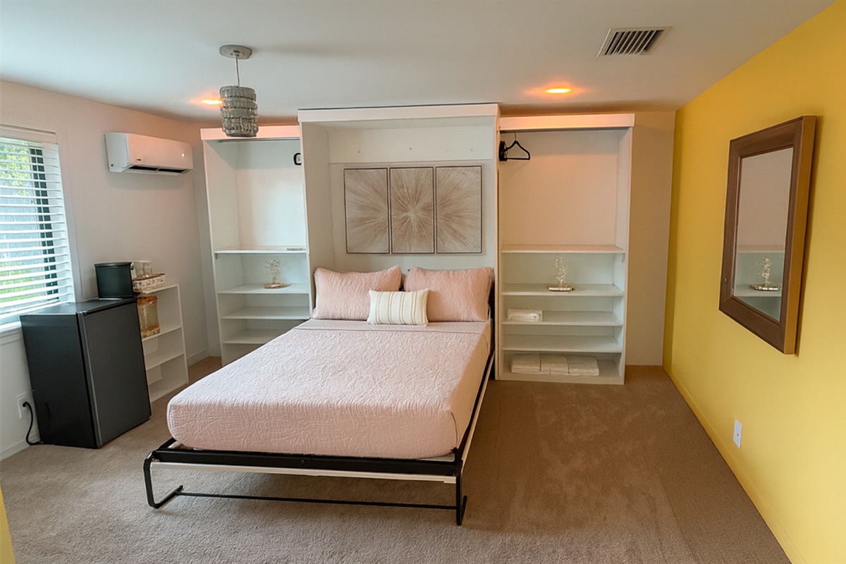 The Gold Room at Garden of Manors, featuring a spacious bed framed by built-in closets, soft lighting, and warm gold accents in Wilton Manors.