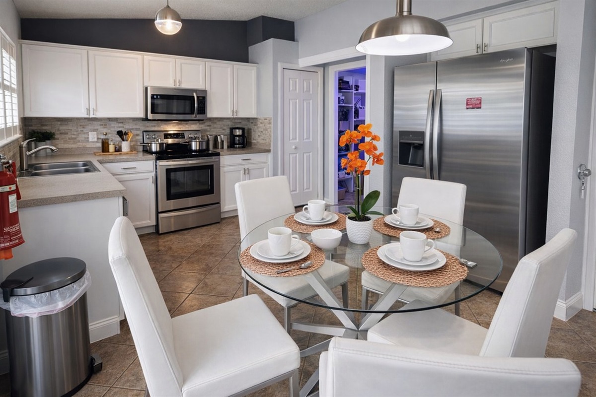 Modern kitchen with stainless steel appliances and a glass dining table set for four.