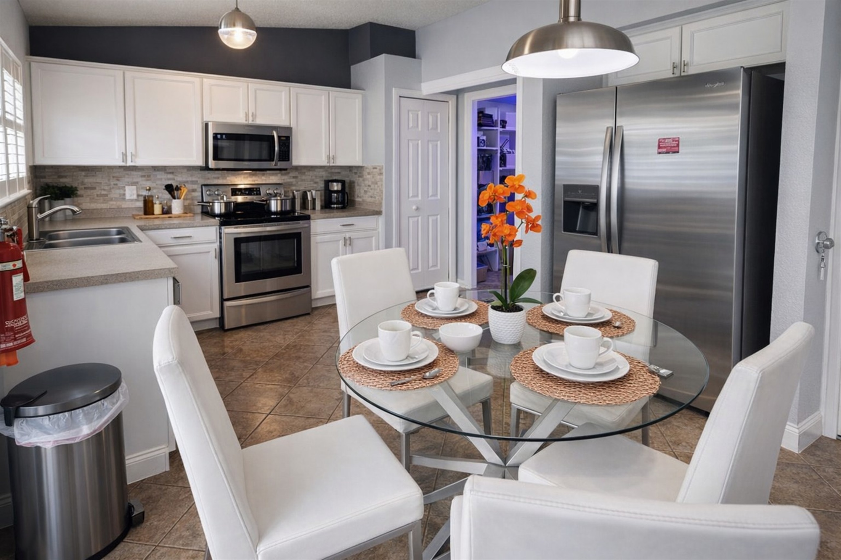 Modern kitchen with stainless steel appliances and a glass dining table set for four.