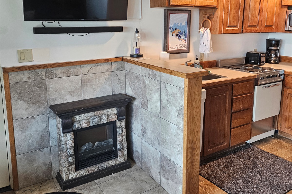 Electric fireplace next to kitchen.