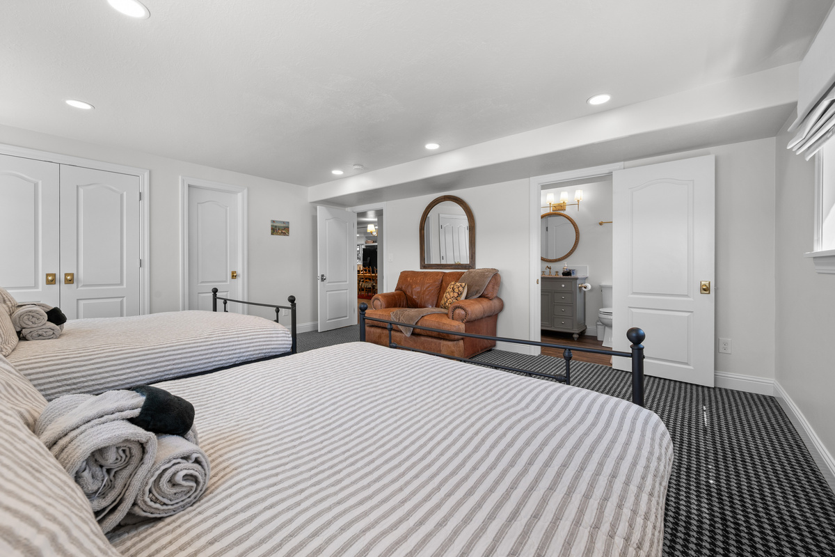 This spacious bedroom features two queen beds, a private ensuite bathroom, ample closet storage, and a relaxed sitting area, creating a refined retreat for families or guests traveling together.