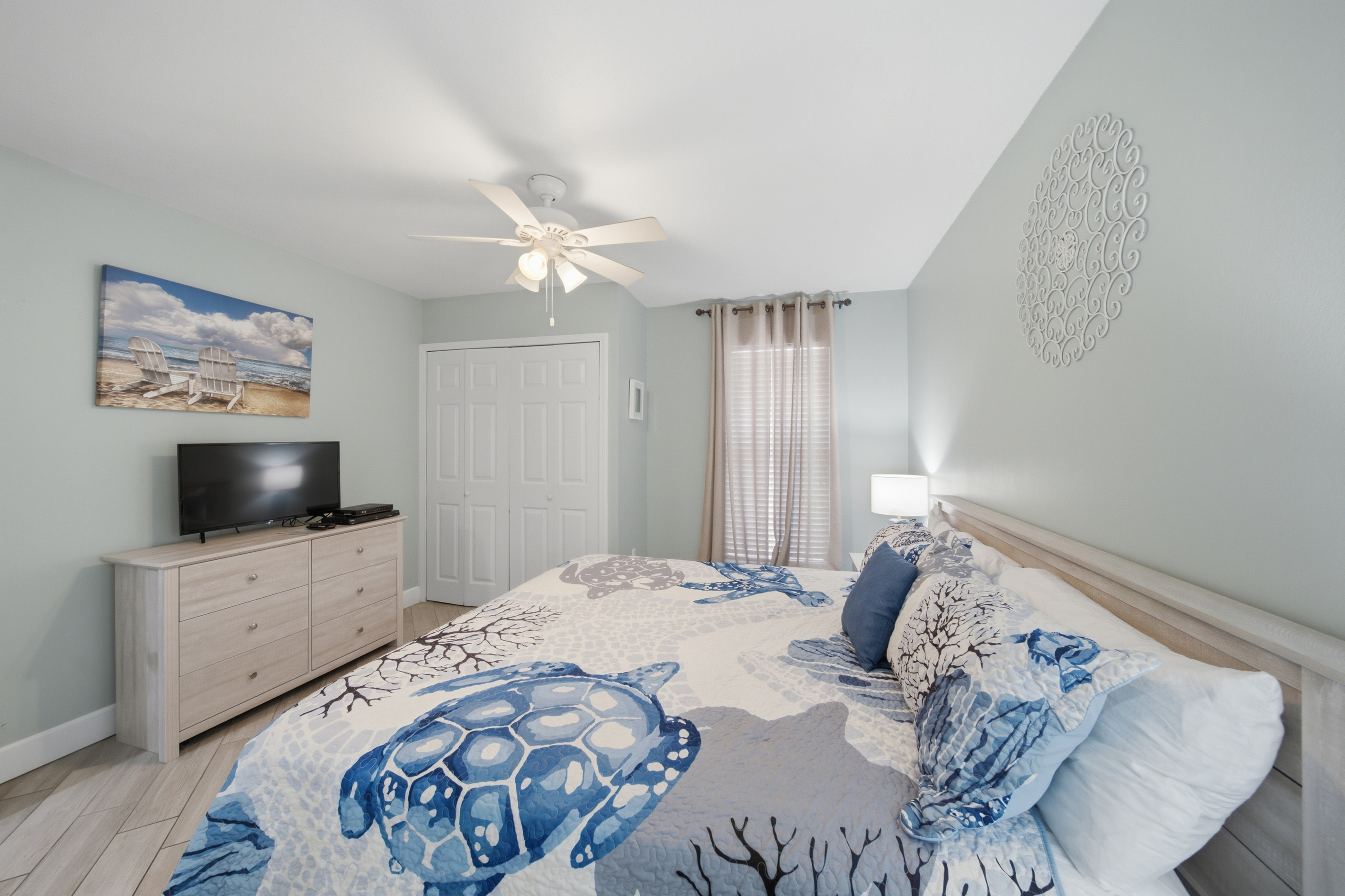 Primary bedroom with dresser, mounted TV, and ceiling fan