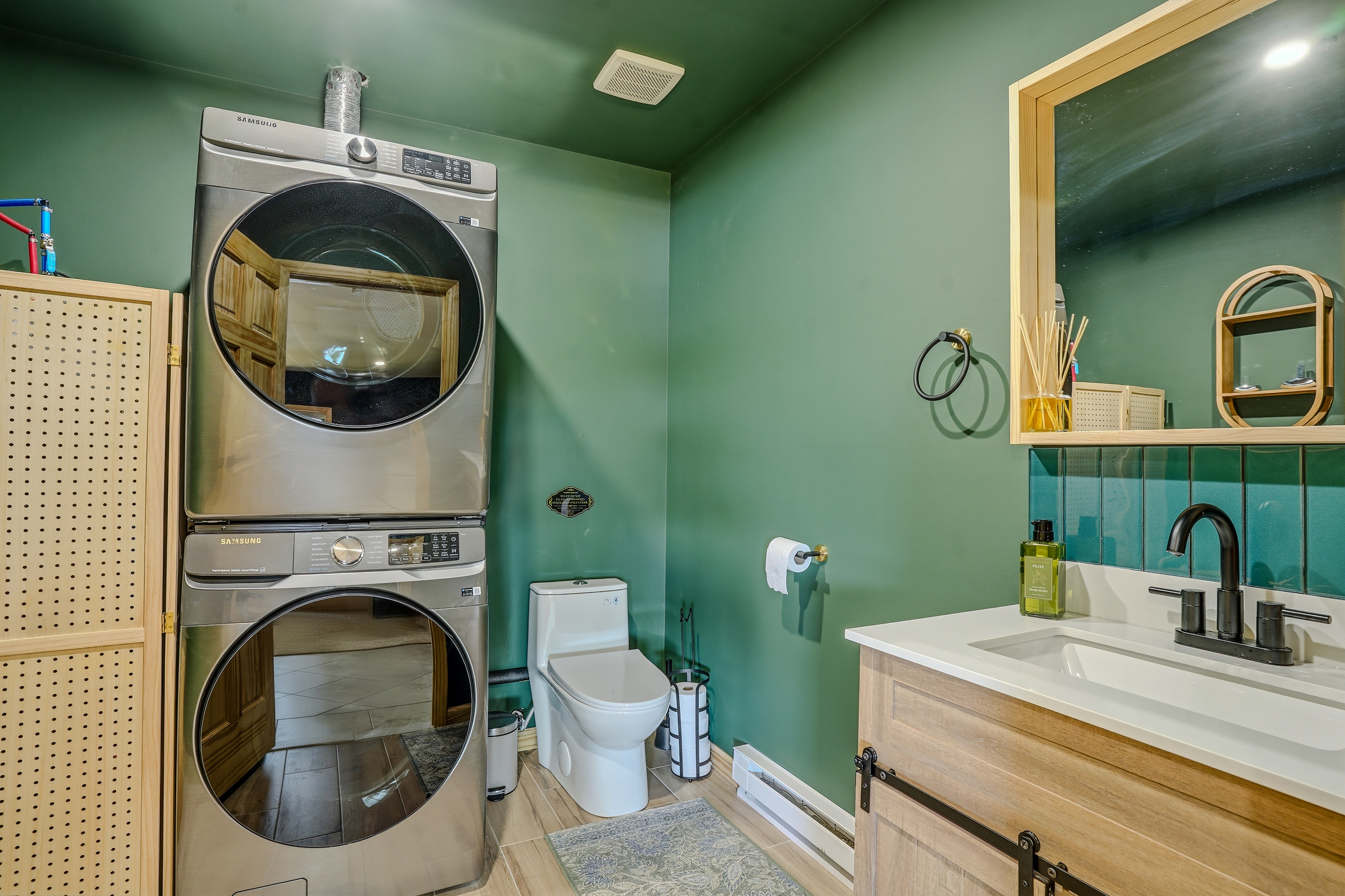 Laundry room with stacked washer/dryer, teal walls, and half bath combo