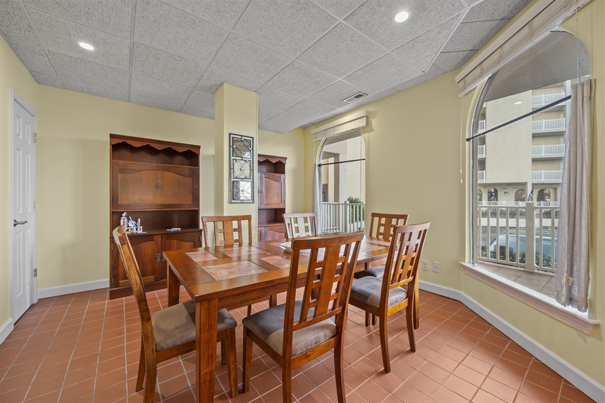 Dedicated dining space with generous seating, natural light from arched windows, and easy access to the main living area