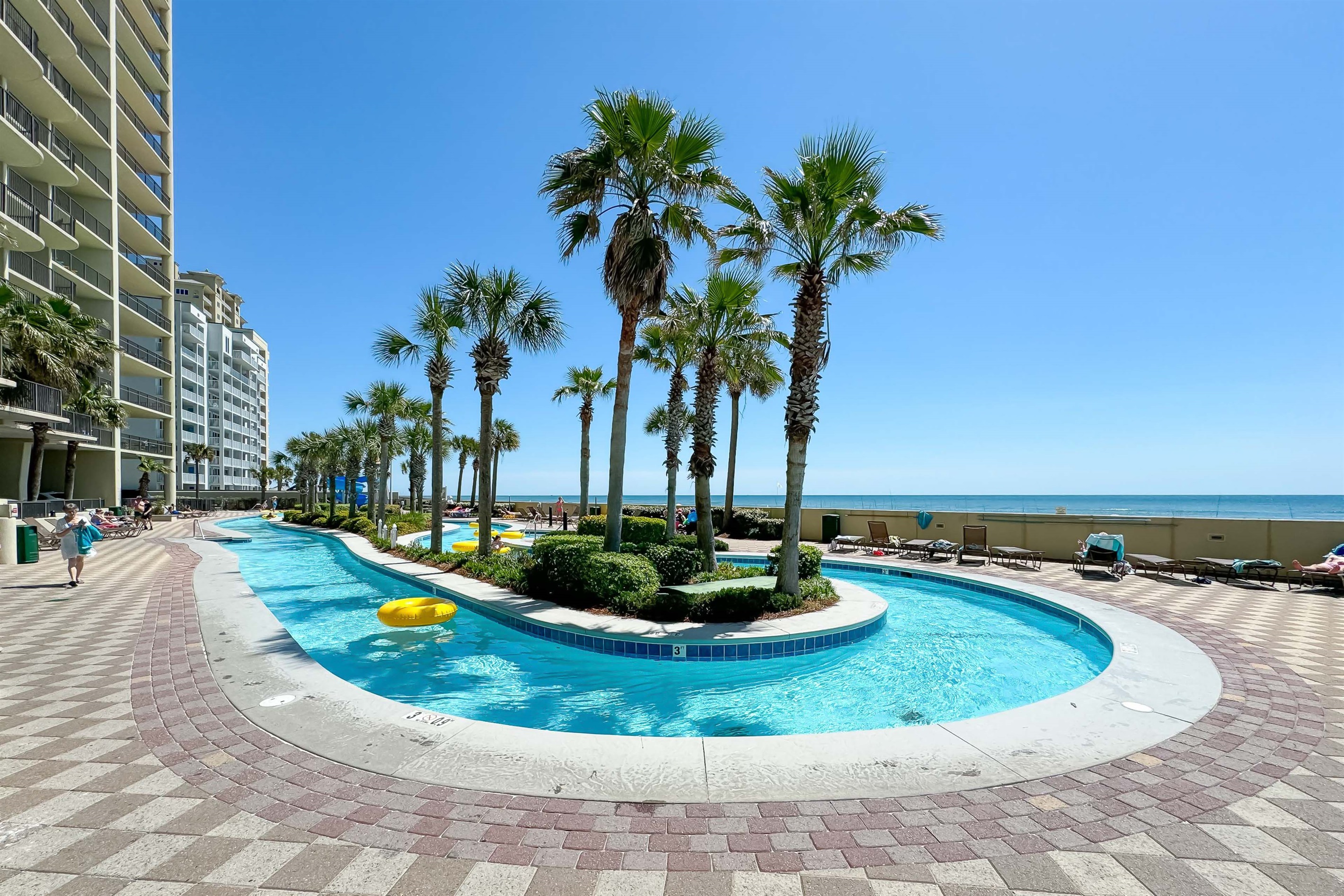 Spacious pool deck and winding lazy river at Phoenix West —experience luxury beachfront living in Orange Beach with pools, slides, and stunning Gulf views.
