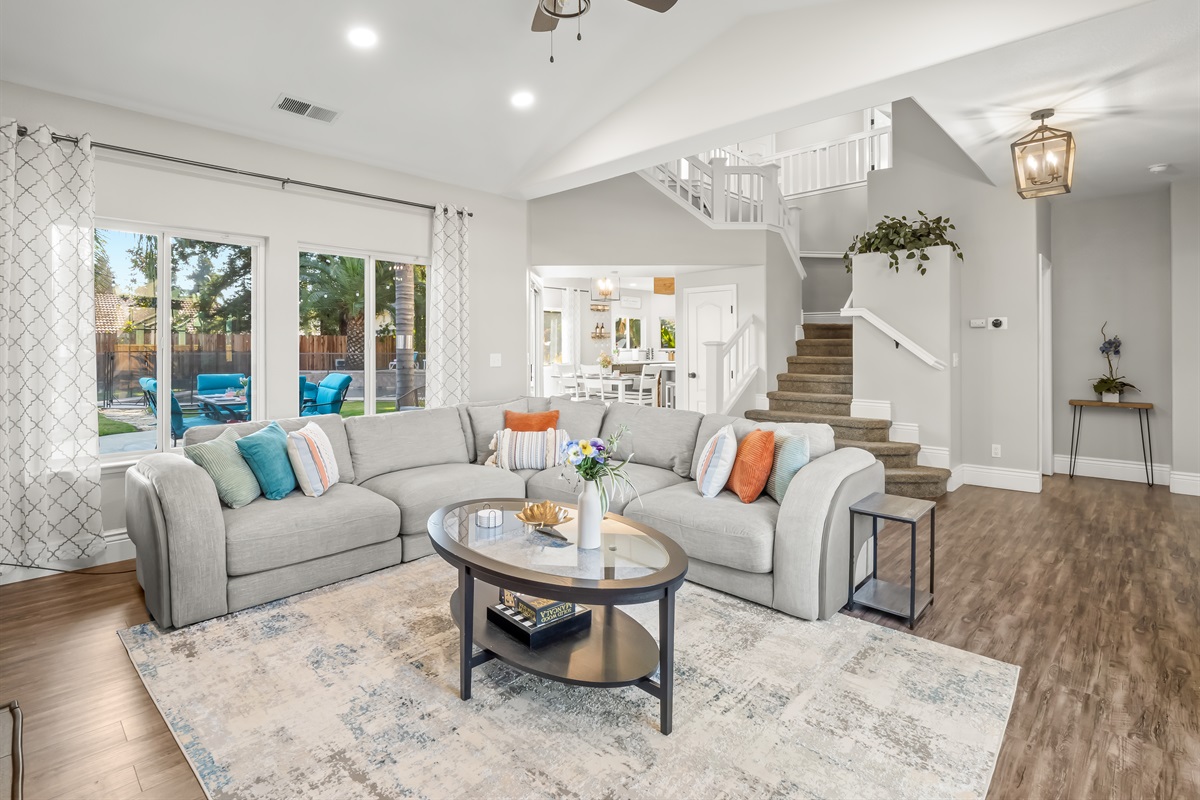 Bright and spacious living room with vaulted ceilings and plenty of comfortable seating—perfect for family movie nights, game time, or relaxing together after a day in the pool.