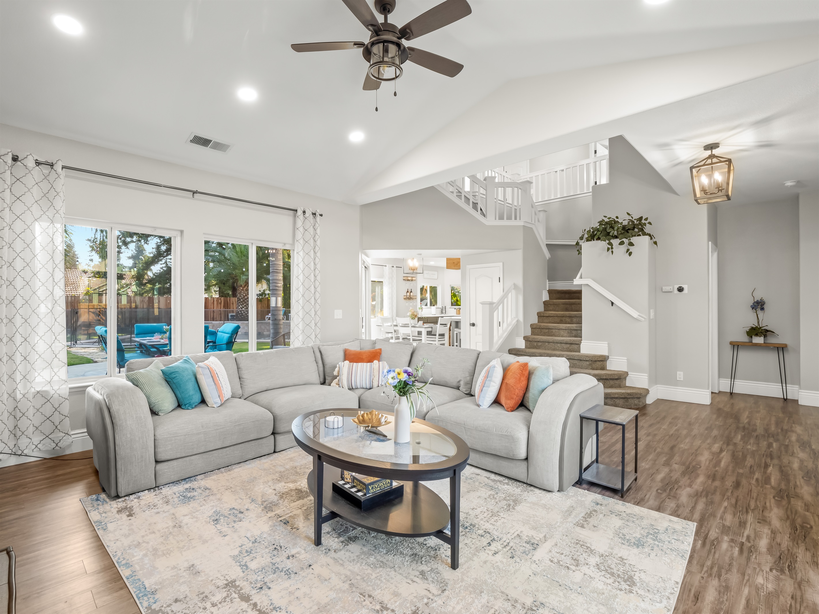 Bright and spacious living room with vaulted ceilings and plenty of comfortable seating—perfect for family movie nights, game time, or relaxing together after a day in the pool.
