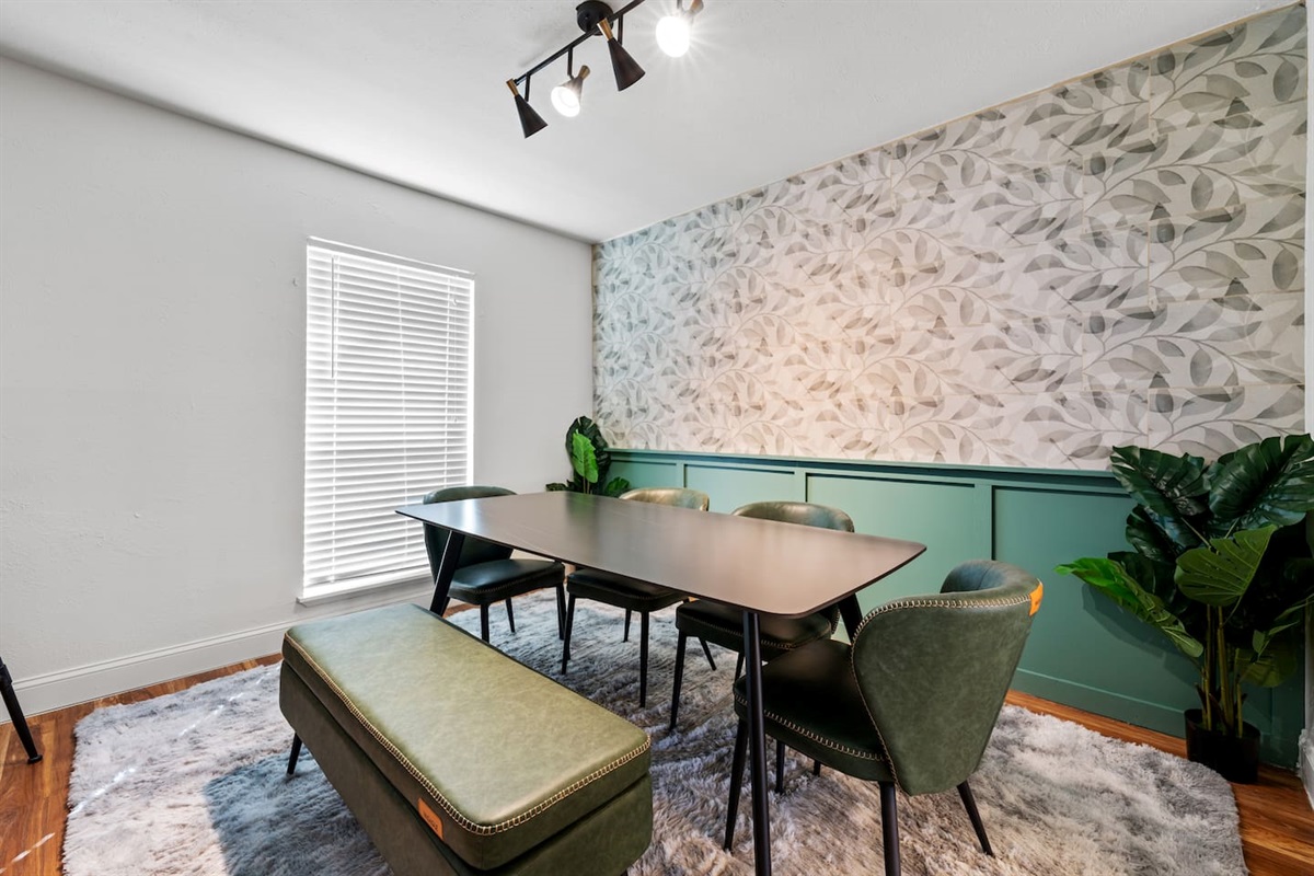 Dine in style with this open-concept layout featuring a spacious table, large windows, and a fully stocked kitchen just steps away.
