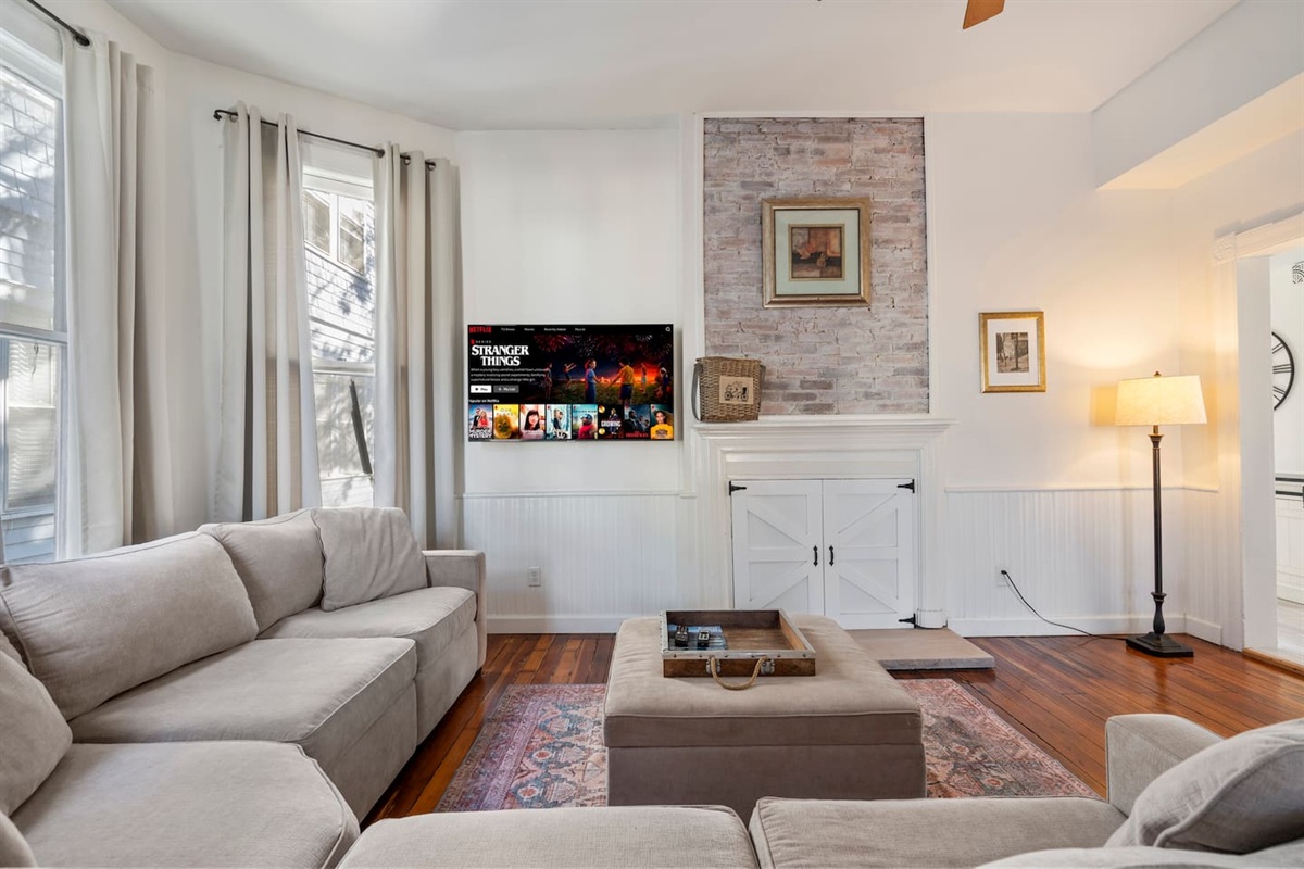 Spacious living room with original hardwood floors and large windows — light-filled and inviting