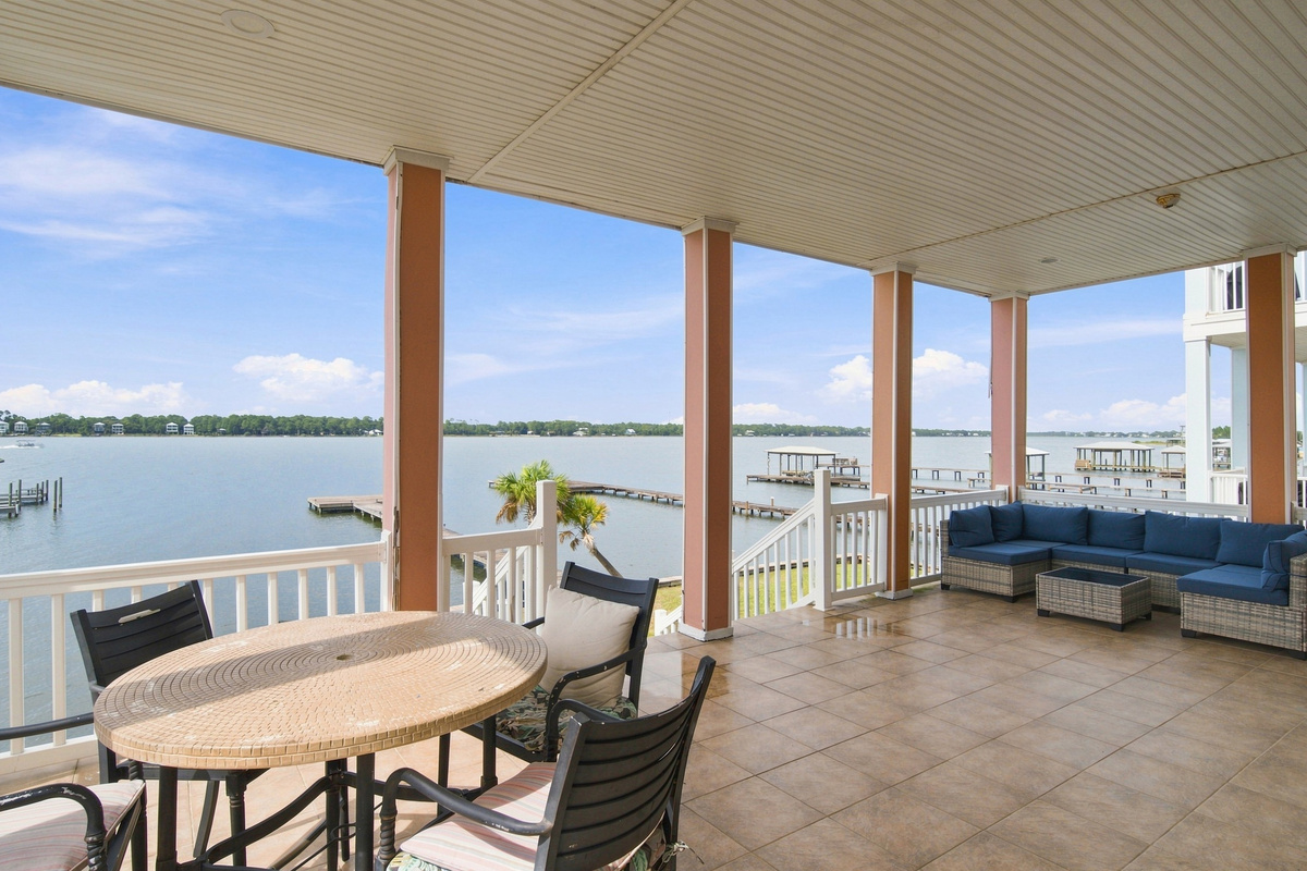 Covered waterfront balcony with dining and seating over Little Lagoon