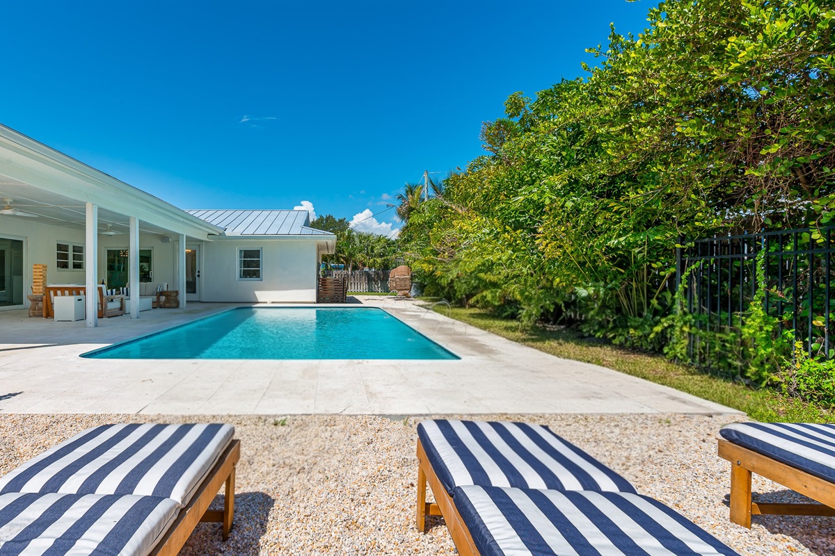 The pool deck is finished in shell white limestone, offering a beautiful natural backdrop.  By night, enjoy the tiki bar, TV, fire table, and the glow of the Jupiter Lighthouse Beacon 