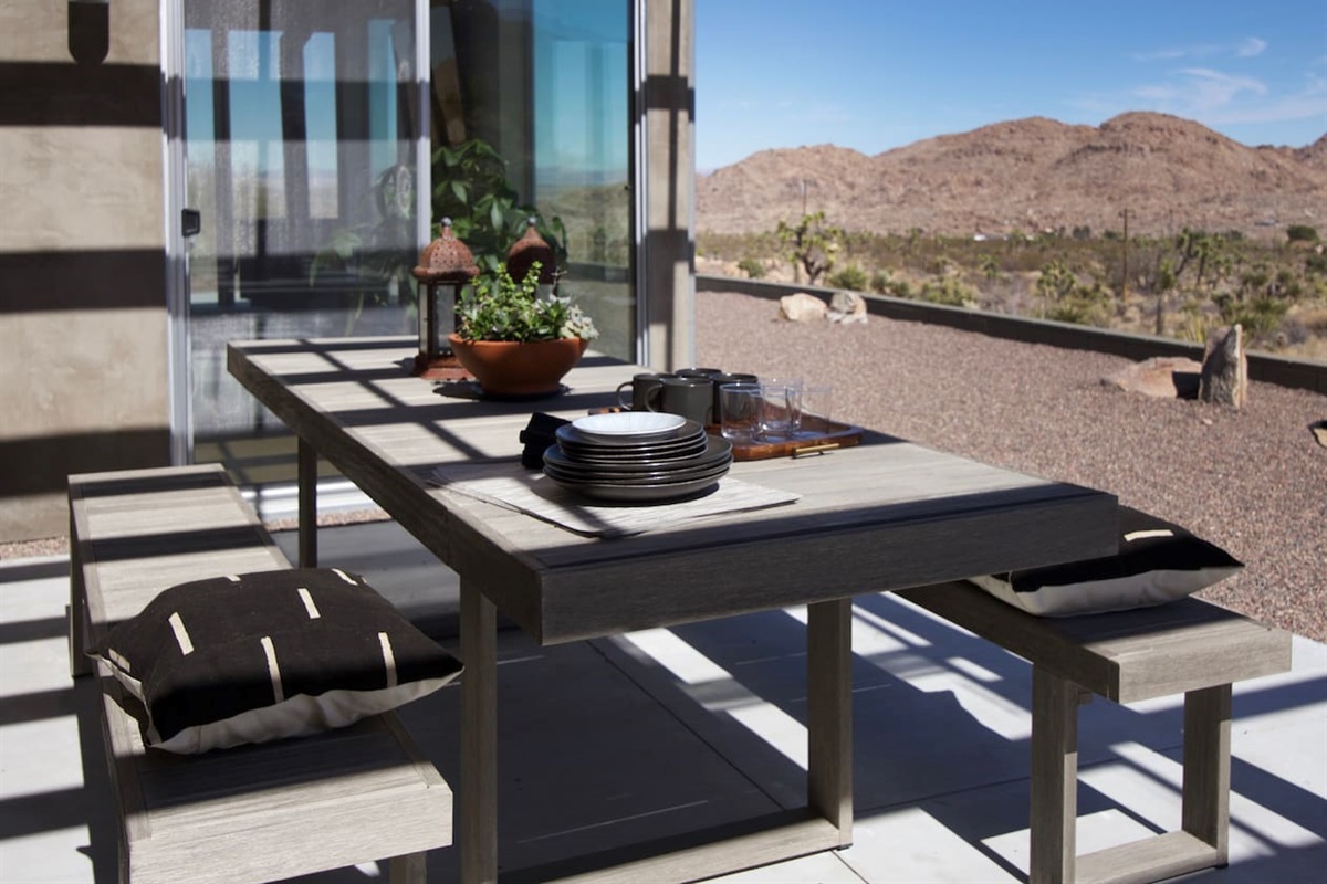 Enjoy meals at the outdoor dining table while taking in sweeping Joshua Tree desert and mountain views.