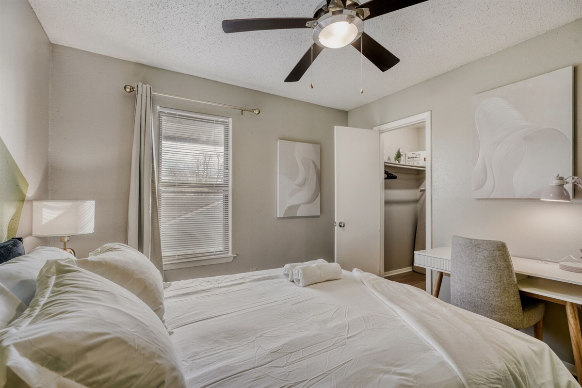 Bright and cozy bedroom with soft tones, a ceiling fan, and a tidy workspace.