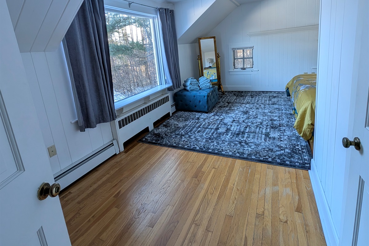 Light-filled bedroom offering generous space, comfortable furnishings, and a peaceful atmosphere.