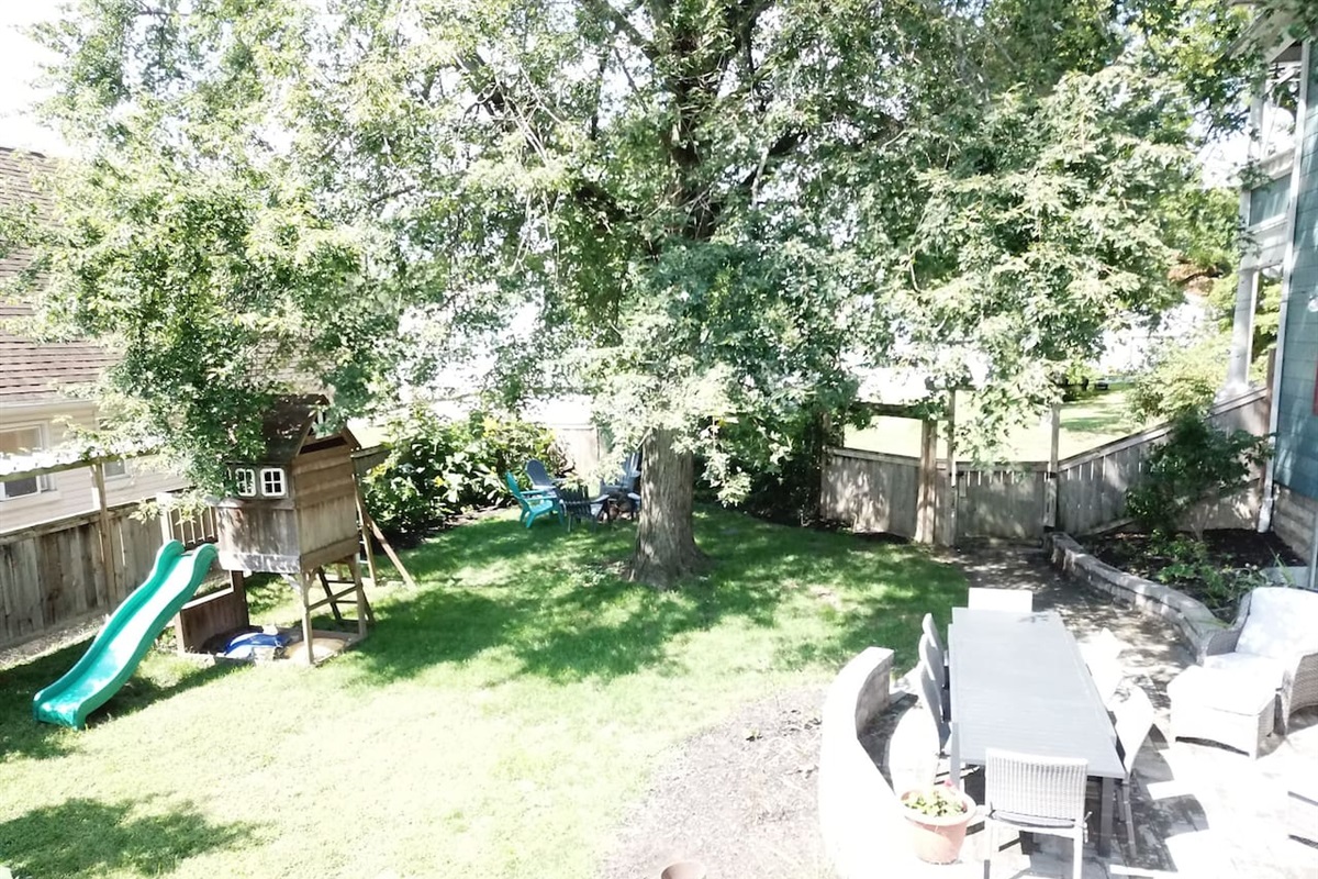 Private, fenced yard offers large dining table, seating area, playset, firepit, gas grill and room for yard games.