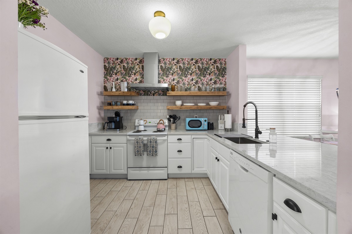 Bright, modern kitchen with white cabinetry, floral accents, and open shelving for a fresh coastal feel.