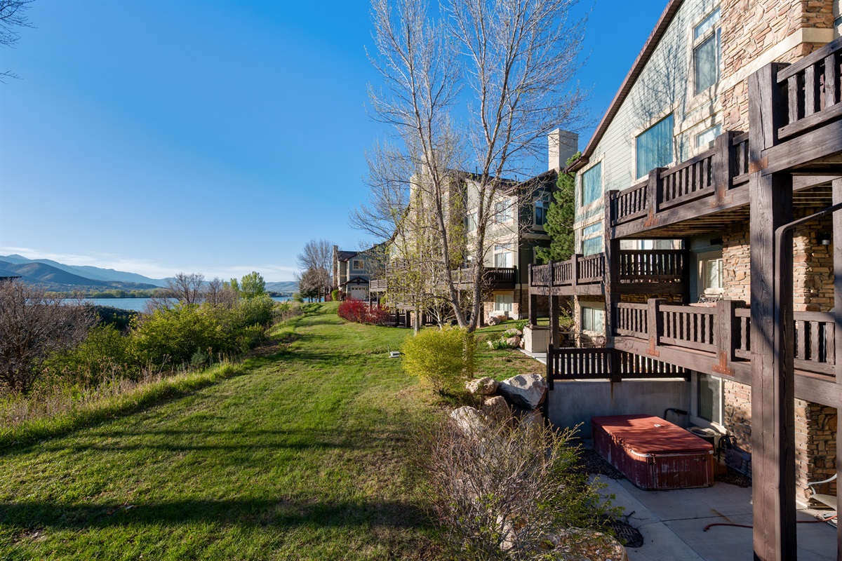 Peaceful community setting with open green space, mature trees, and mountain and lake surroundings.