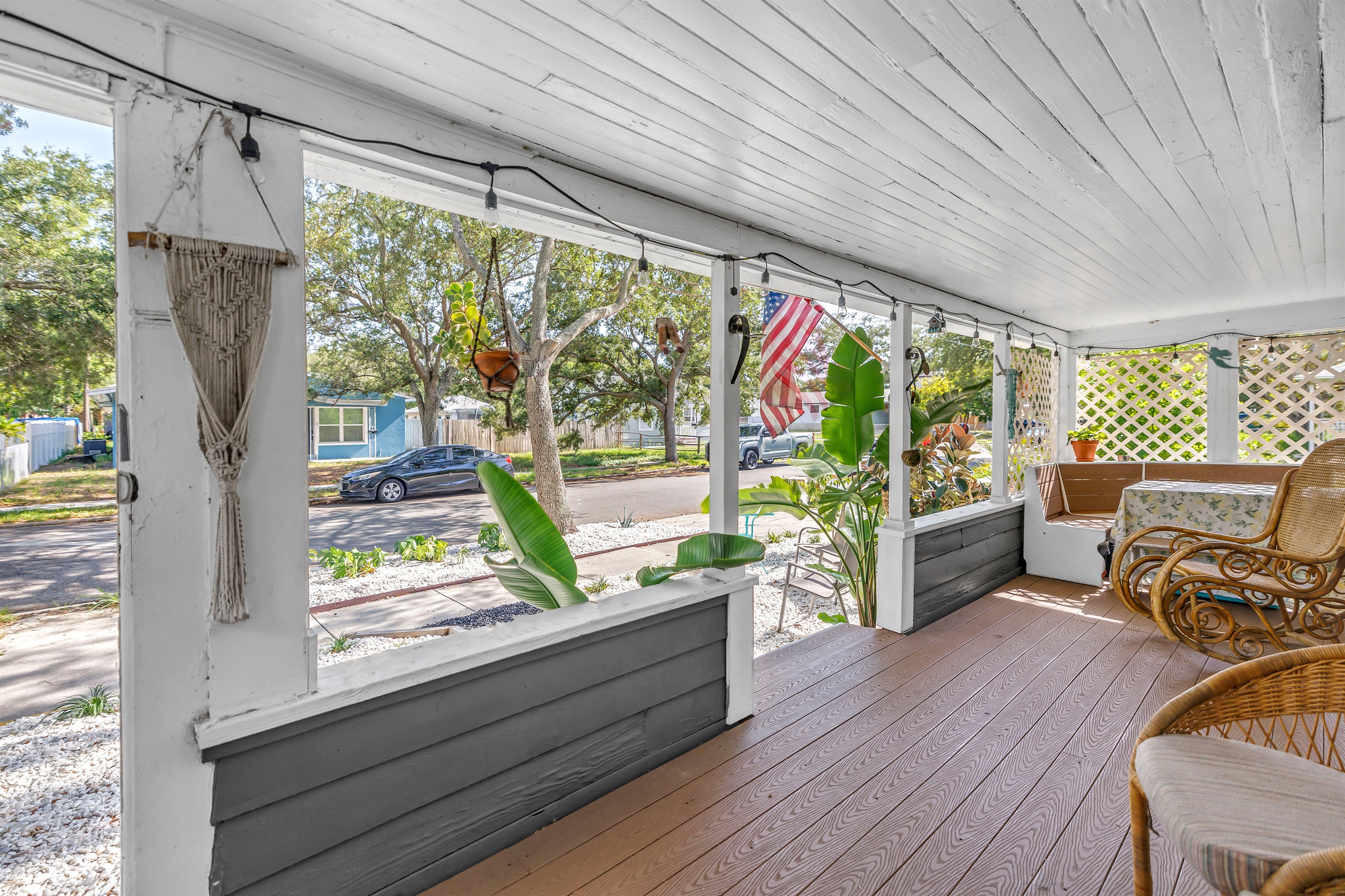 porch with cozy seating, string lights, and a peaceful view of the fenced yard and tropical landscaping.