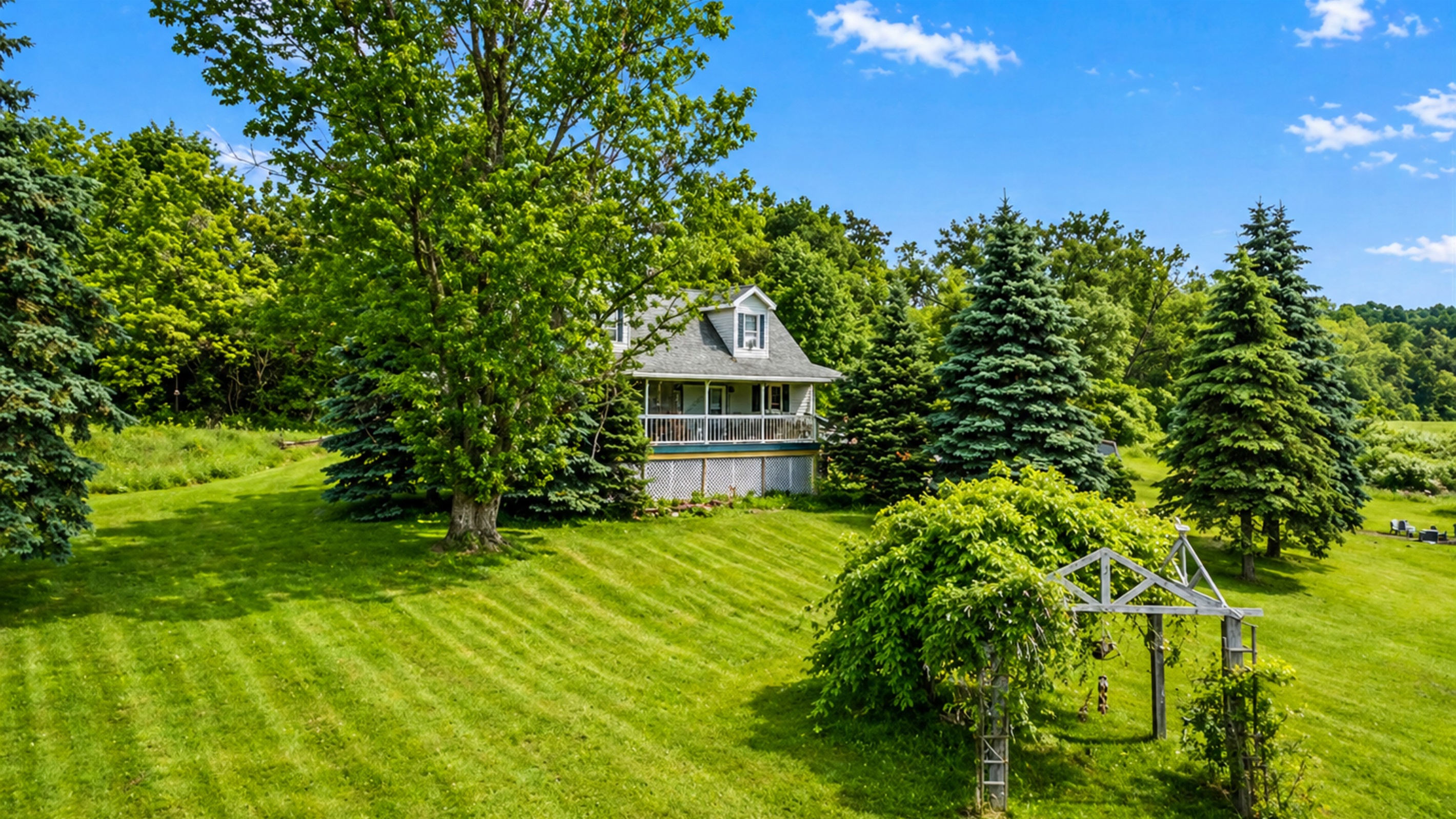 This serene property boasts a charming house surrounded by lush greenery and tall trees, offering a peaceful retreat.
