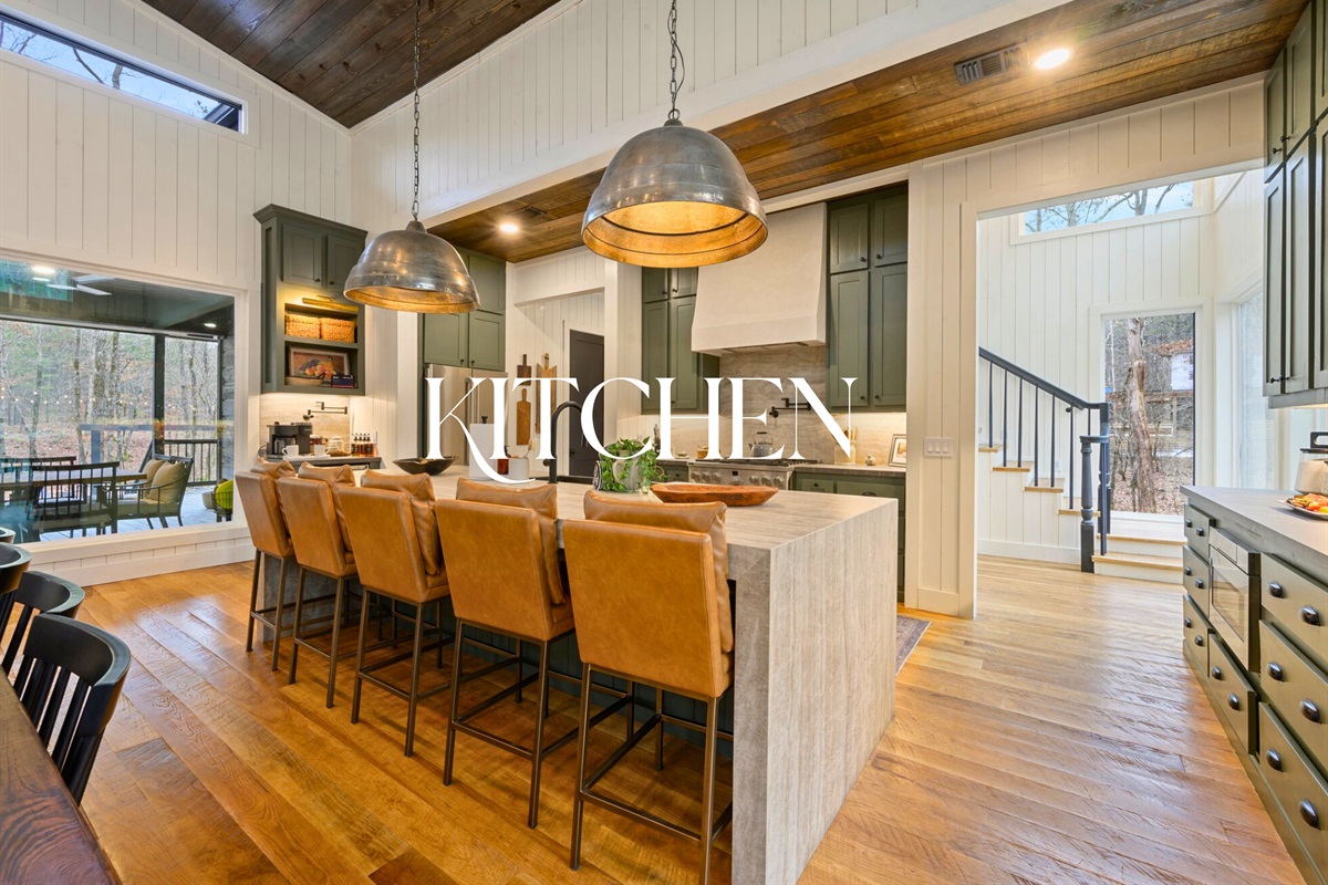 The kitchen island offers generous seating and modern lighting, making it a natural gathering point for snacks and casual meals.