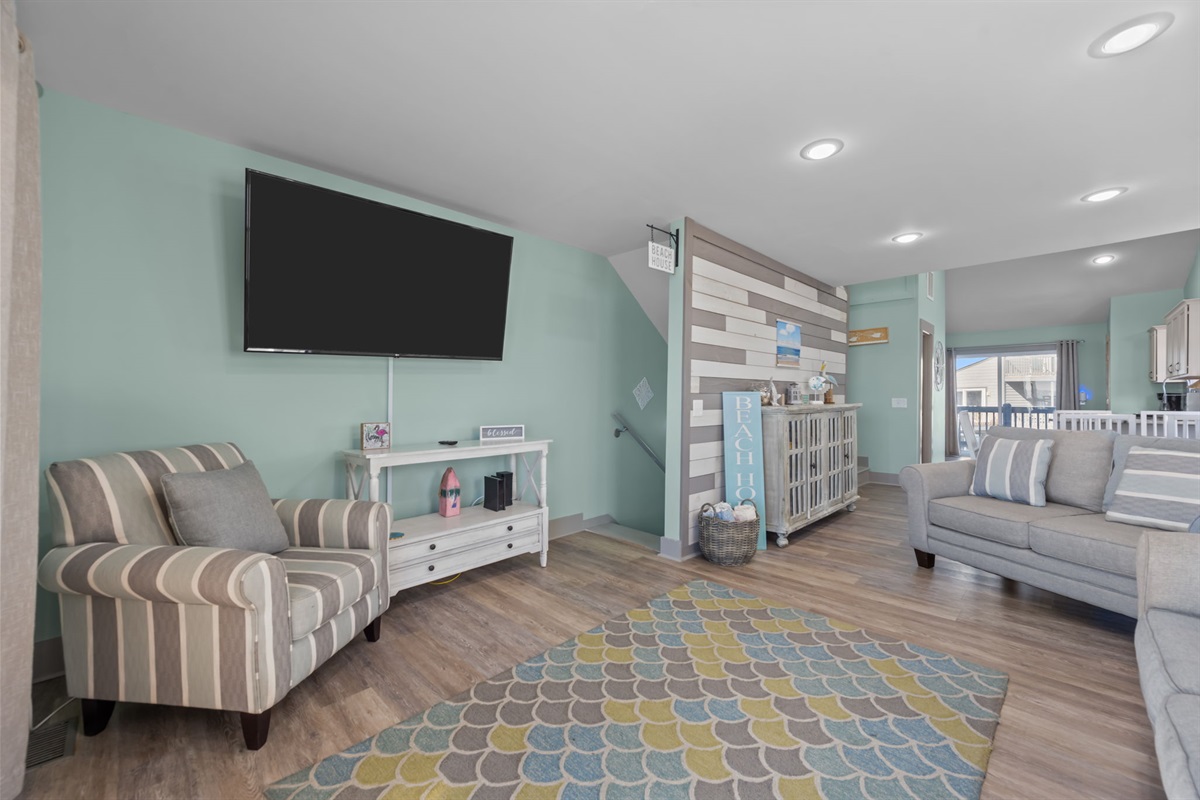 Relax in this cozy living area featuring a large flat-screen TV and comfortable seating: perfect for movie nights or unwinding after a day at the beach