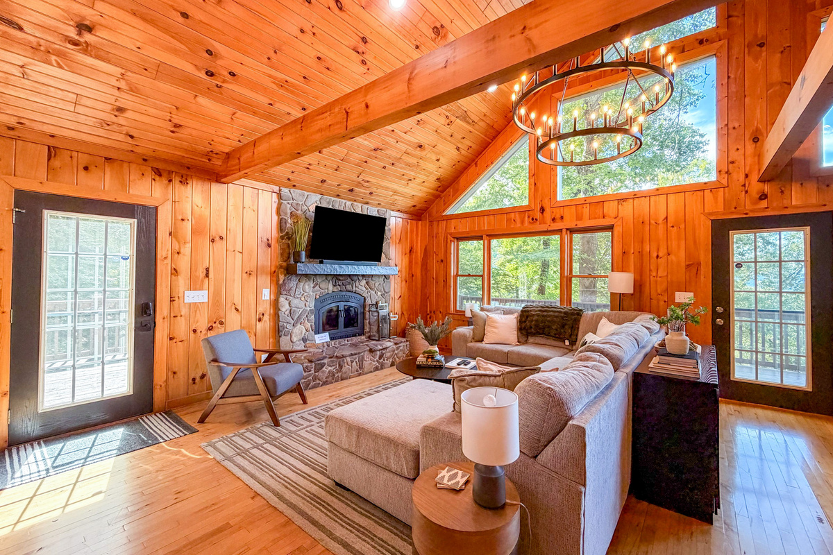 Step into our serene living room, where lush green foliage frames every window(please note there is no fireplace listed as an amenity).