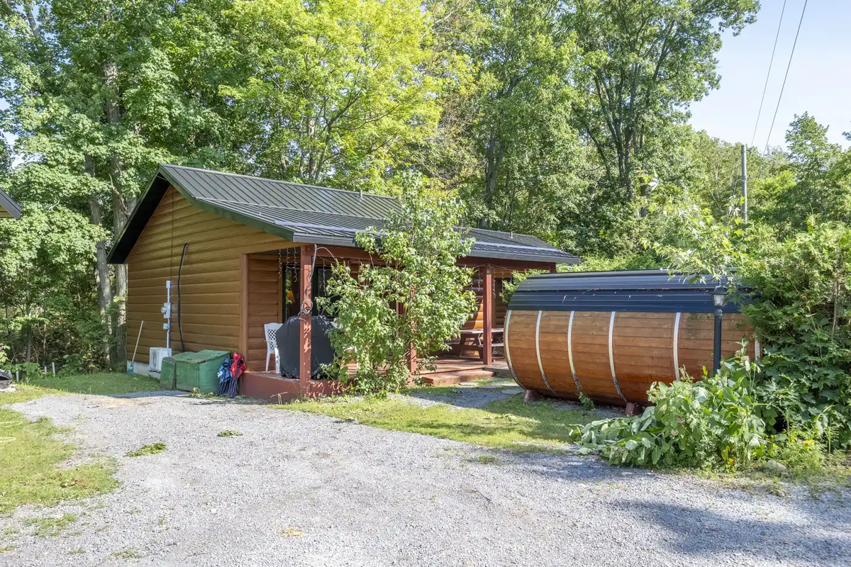Cottage #5 surrounded by trees with barrel sauna nearby